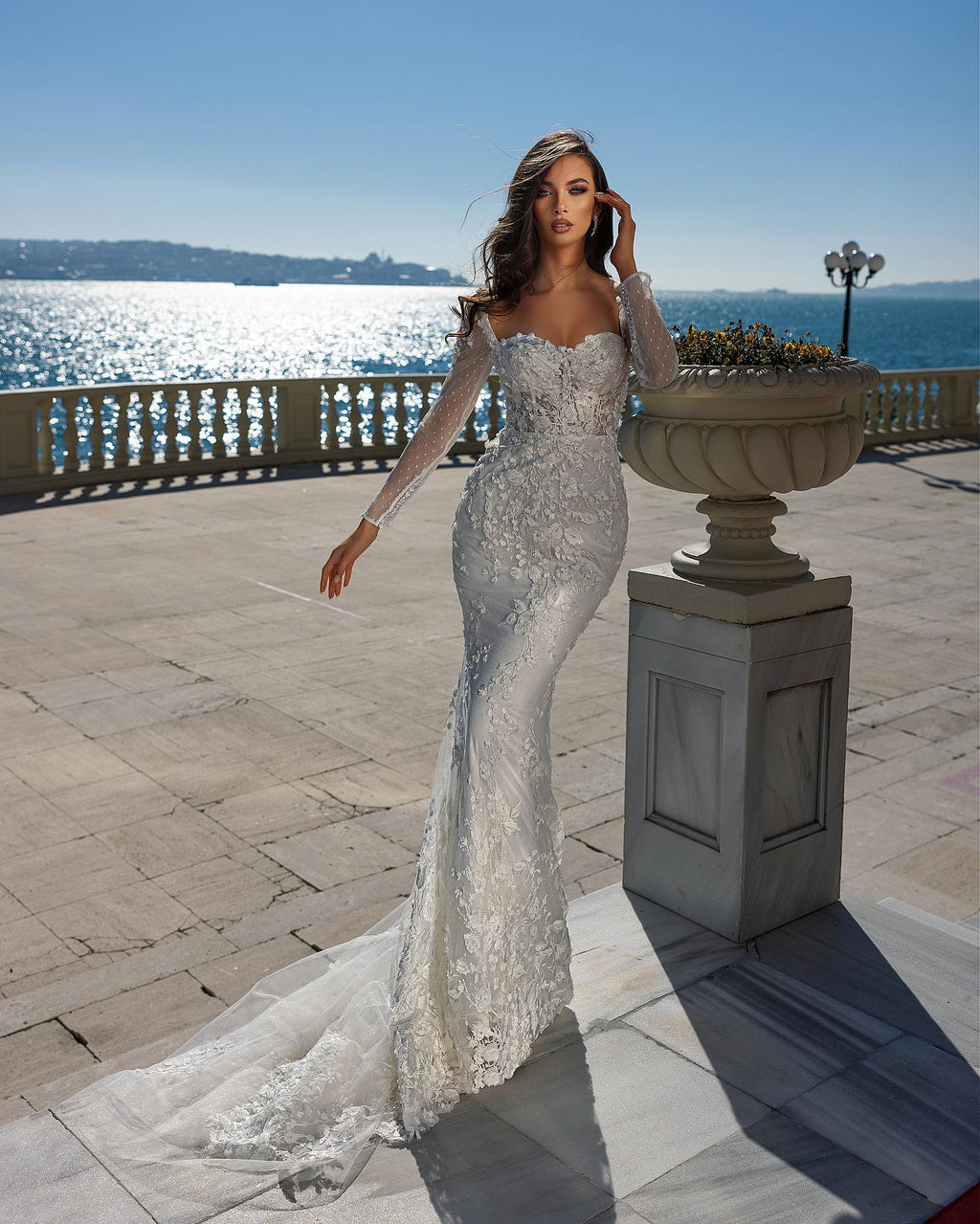 Precioso vestido de novia de sirena con escote corazón, manga larga, encaje y cola desmontable.