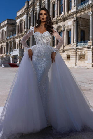 Precioso vestido de novia de sirena con escote corazón, manga larga, encaje y cola desmontable.