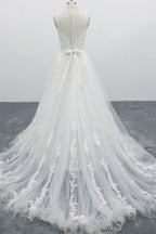 Robe de mariée longue et élégante en tulle dos nu, coupe trapèze et ornée d'appliqués.