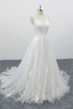 Robe de mariée longue et élégante en tulle dos nu, coupe trapèze et ornée d'appliqués.