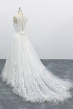 Robe de mariée longue et élégante en tulle dos nu, coupe trapèze et ornée d'appliqués.
