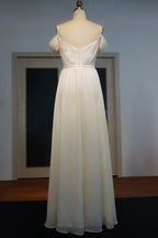 Robe de bal en mousseline ivoire à bretelles spaghetti, décolleté cœur et ourlet trapèze, longueur au sol, volants, ourlet spaghetti.