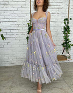 Vestido de fiesta de tul color lila, corte en A y largo hasta la rodilla, con bordados.