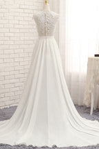 Robe de mariée longue en mousseline de soie ornée d'appliqués de dentelle et fendue, coupe trapèze.