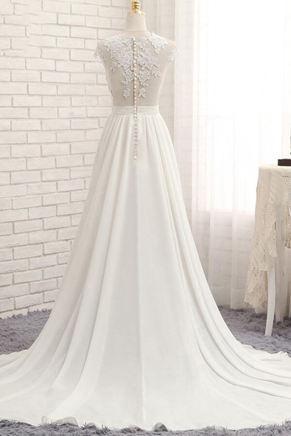 Robe de mariée longue en mousseline de soie ornée d'appliqués de dentelle et fendue, coupe trapèze.
