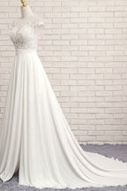 Robe de mariée longue en mousseline de soie ornée d'appliqués de dentelle et fendue, coupe trapèze.