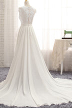 Robe de mariée longue en mousseline de soie ornée d'appliqués de dentelle et fendue, coupe trapèze.