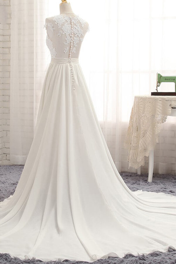 Robe de mariée longue en mousseline de soie ornée d'appliqués de dentelle et fendue, coupe trapèze.