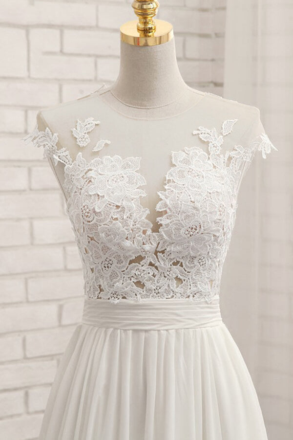 Robe de mariée longue en mousseline de soie ornée d'appliqués de dentelle et fendue, coupe trapèze.