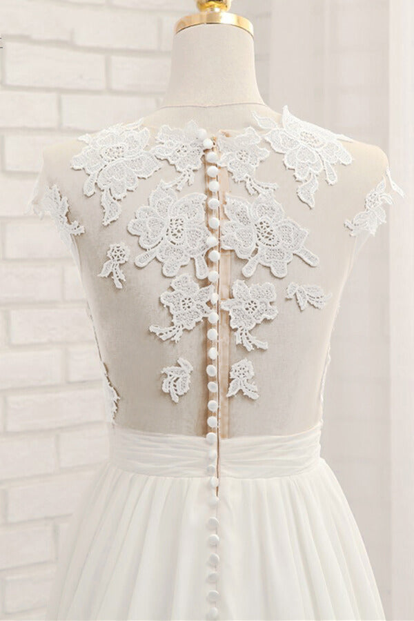 Robe de mariée longue en mousseline de soie ornée d'appliqués de dentelle et fendue, coupe trapèze.