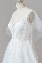 Robe de mariée longue en tulle et dentelle à manches, coupe trapèze, ornée d'appliqués.
