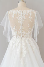 Robe de mariée longue en tulle et dentelle à manches, coupe trapèze, ornée d'appliqués.