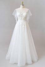 Robe de mariée longue en tulle et dentelle à manches, coupe trapèze, ornée d'appliqués.
