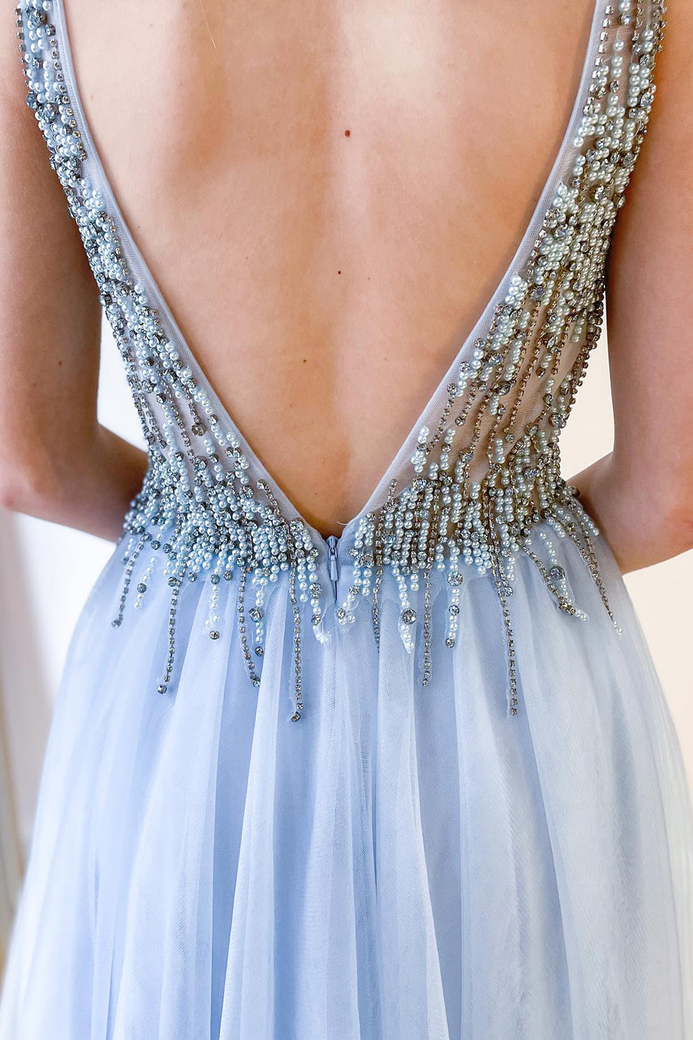 Robe de bal longue trapèze en tulle à décolleté en V profond et dos nu fendu, ornée de perles et fendue.