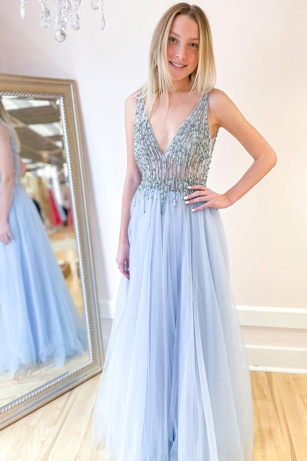 Robe de bal longue trapèze en tulle à décolleté en V profond et dos nu fendu, ornée de perles et fendue.