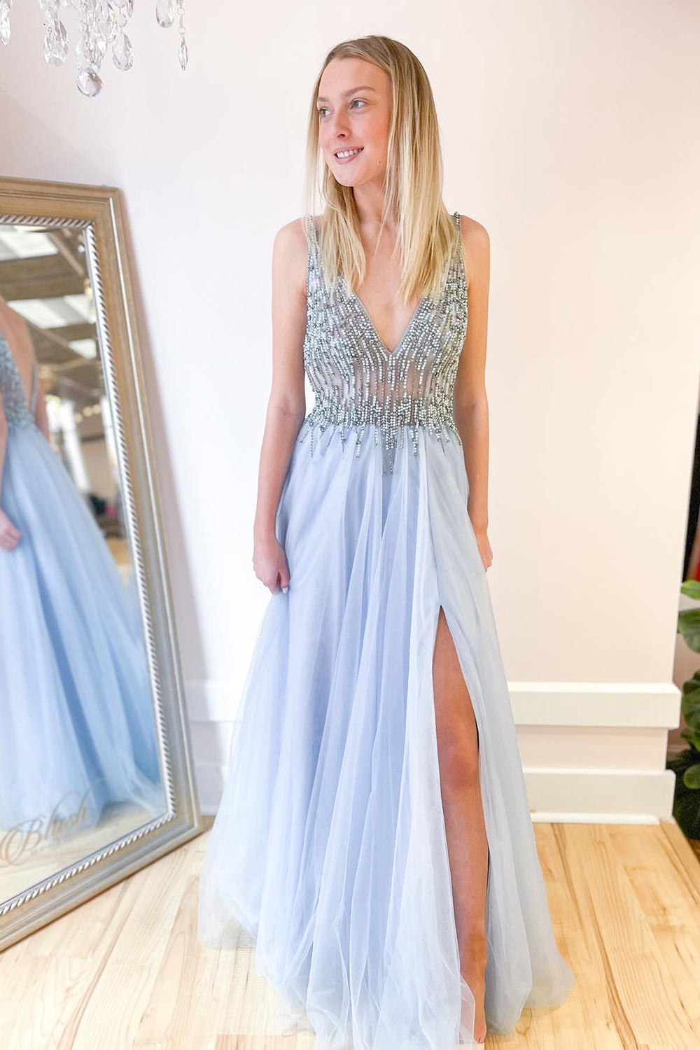 Robe de bal longue trapèze en tulle à décolleté en V profond et dos nu fendu, ornée de perles et fendue.