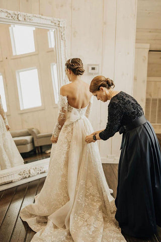 Vestido de novia largo de encaje con corte en A, hombros descubiertos y mangas, estilo línea A.