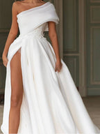 Robe de mariée longue en mousseline de soie, coupe trapèze asymétrique, traîne balai et fente.