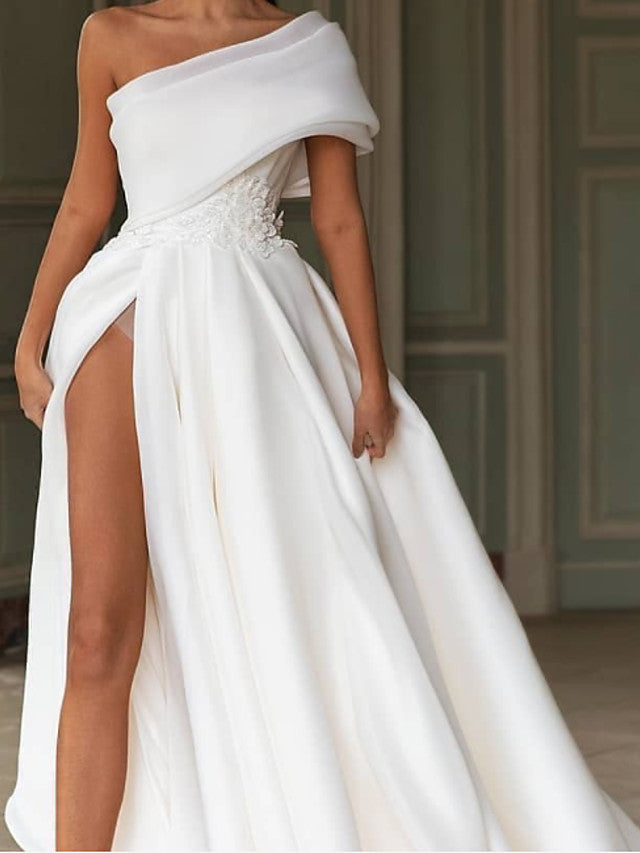 Robe de mariée longue en mousseline de soie, coupe trapèze asymétrique, traîne balai et fente.