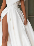 Robe de mariée longue en mousseline de soie, coupe trapèze asymétrique, traîne balai et fente.