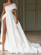 Robe de mariée longue en mousseline de soie, coupe trapèze asymétrique, traîne balai et fente.
