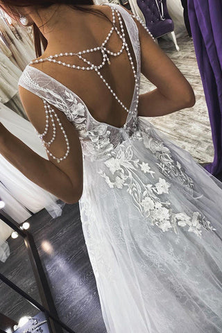 Vestido de novia de corte sirena con tirantes largos, escote en V, apliques de perlas y espalda descubierta.