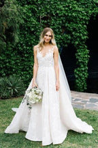Vestido de novia de corte sirena con tirantes largos, escote en V, cuentas florales, tul y espalda descubierta.