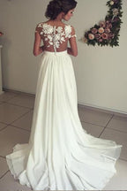 Robe de mariée longue en mousseline de soie ornée d'appliqués de dentelle et d'un décolleté en cœur, avec fente, coupe trapèze et décolleté cœur.