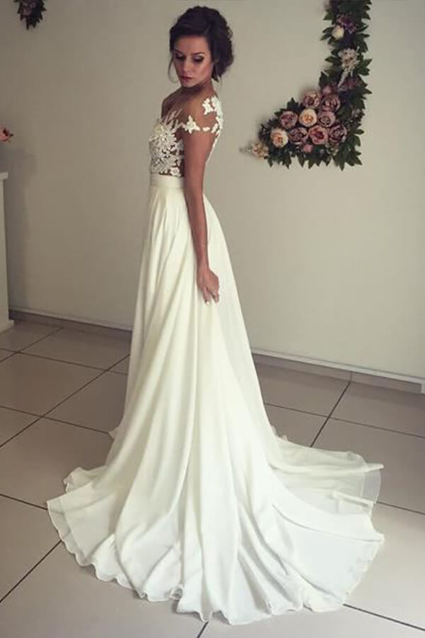 Robe de mariée longue en mousseline de soie ornée d'appliqués de dentelle et d'un décolleté en cœur, avec fente, coupe trapèze et décolleté cœur.