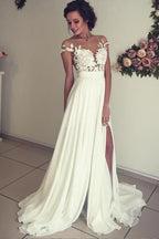 Robe de mariée longue en mousseline de soie ornée d'appliqués de dentelle et d'un décolleté en cœur, avec fente, coupe trapèze et décolleté cœur.