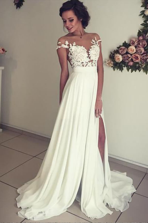 Robe de mariée longue en mousseline de soie ornée d'appliqués de dentelle et d'un décolleté en cœur, avec fente, coupe trapèze et décolleté cœur.