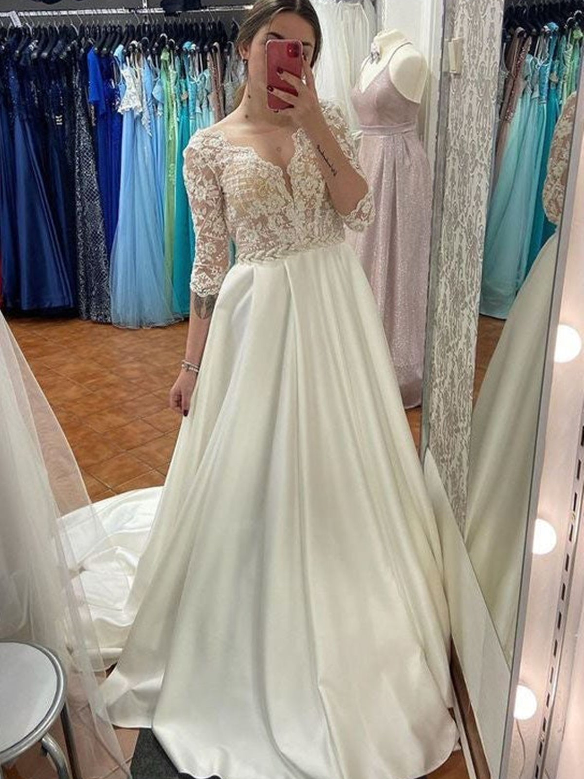 Robe de mariée longue en satin et dentelle, coupe trapèze, décolleté cœur, manches, couleur ivoire.