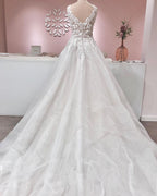 Robe de mariée longue trapèze en tulle à volants, dos nu, col en V et applications de dentelle, ornée de décolletés en V et d'appliques.