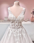 Robe de mariée longue trapèze en tulle à volants, dos nu, col en V et applications de dentelle, ornée de décolletés en V et d'appliques.