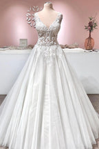 Robe de mariée longue trapèze en tulle à volants, dos nu, col en V et applications de dentelle, ornée de décolletés en V et d'appliques.