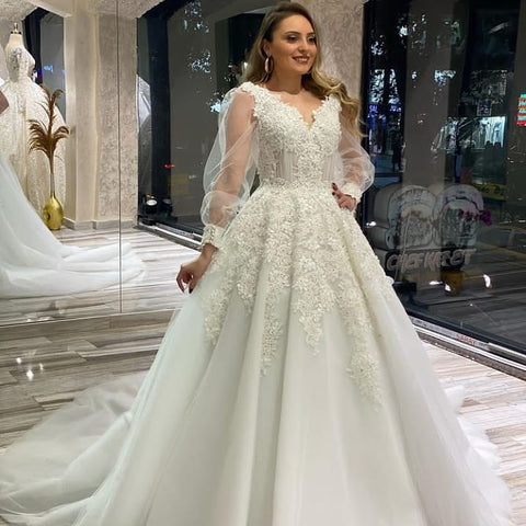 Vestido de novia largo de corte A, escote en V, apliques de encaje y tul con mangas largas abullonadas.