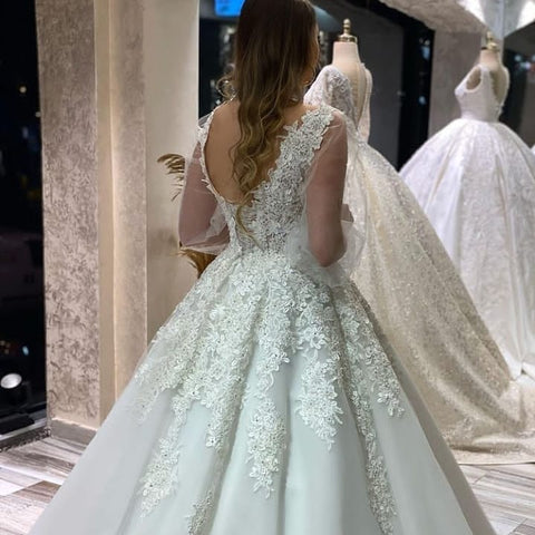 Vestido de novia largo de corte A, escote en V, apliques de encaje y tul con mangas largas abullonadas.