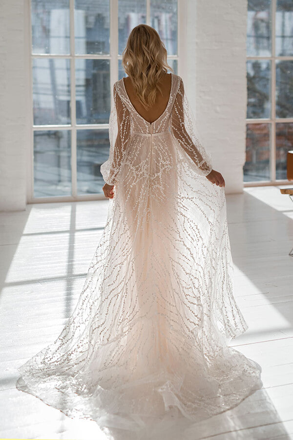 Vestido de novia largo de tul con corte en A, escote en V, cola de corte y mangas, con escote en V y corte asimétrico.