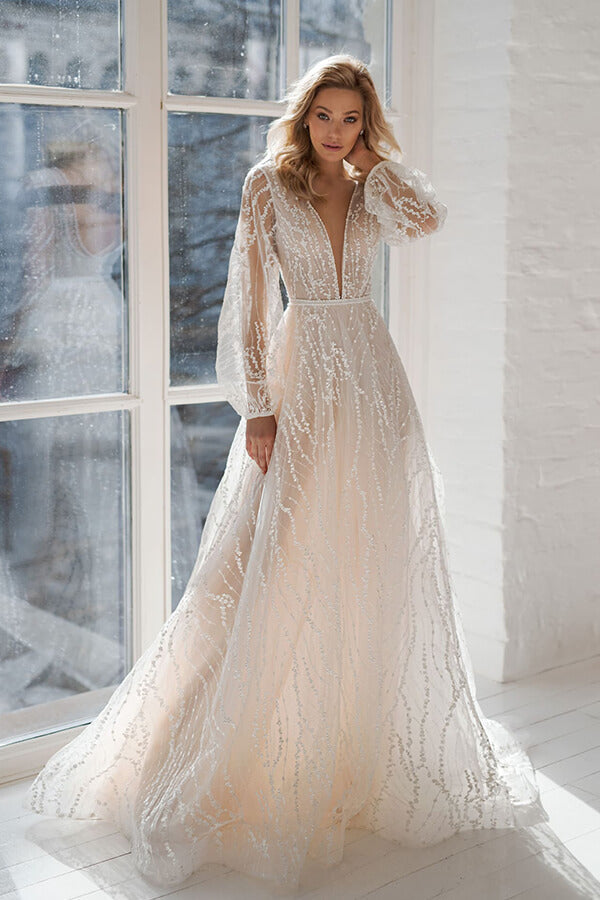 Vestido de novia largo de tul con corte en A, escote en V, cola de corte y mangas, con escote en V y corte asimétrico.