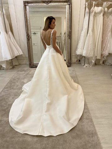 Vestido de novia largo de corte A, escote en V, tirantes finos, espalda descubierta y con bolsillos.
