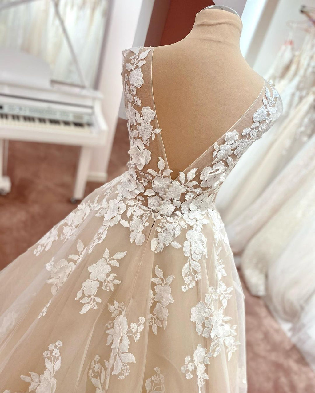 Robe de mariée longue trapèze en tulle et dentelle à bretelles larges et dos nu, ornée d'appliques en dentelle et en tulle, col en V et décolleté en V.