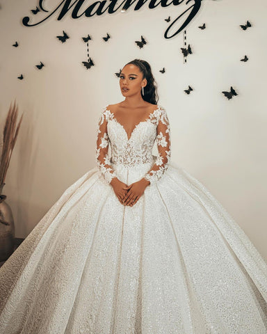 Vestido de novia largo de corte princesa con escote corazón, apliques de encaje, lentejuelas, volantes y mangas.
