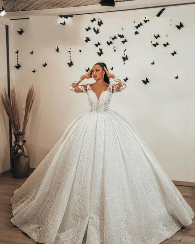 Vestido de novia largo de corte princesa con escote corazón, apliques de encaje, lentejuelas, volantes y mangas.