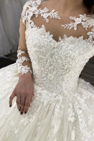 Vestido de novia largo de corte princesa con escote corazón, apliques de encaje y tul, con mangas.