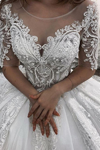 Vestido de novia largo de corte princesa con escote corazón, apliques de encaje y tul, con mangas.