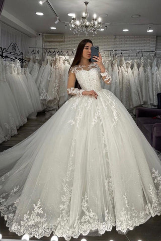 Vestido de novia largo de corte princesa con escote corazón, apliques de encaje y tul, con mangas.