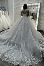 Vestido de novia largo de corte princesa con escote corazón, apliques de encaje y tul, con mangas.