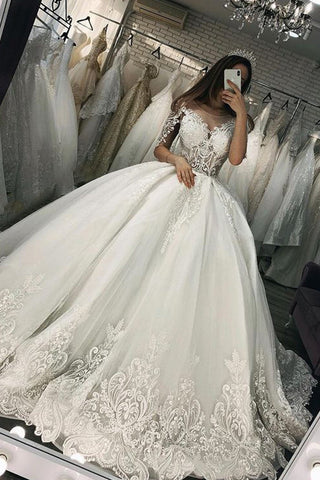 Vestido de novia largo de corte princesa con escote corazón, apliques de encaje y tul, con mangas.