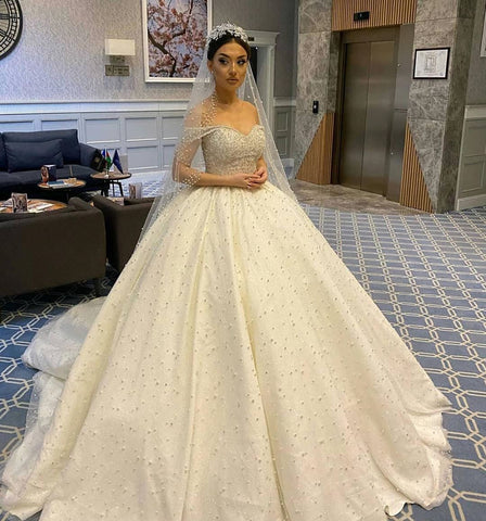 Vestido de novia largo de corte princesa, escote corazón, espalda descubierta, con perlas, volantes y tul.