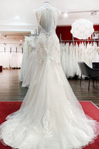 Robe de mariée sirène longue en dentelle, décolleté cœur et dos nu, ornée d'appliqués de dentelle.
